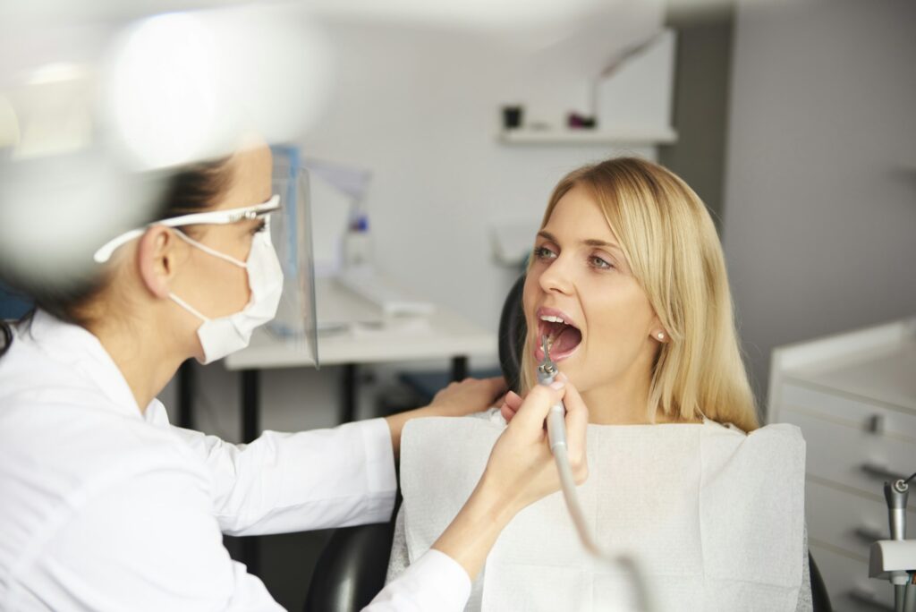 Focused dentist with dental drill cleaning bad patient's teeth